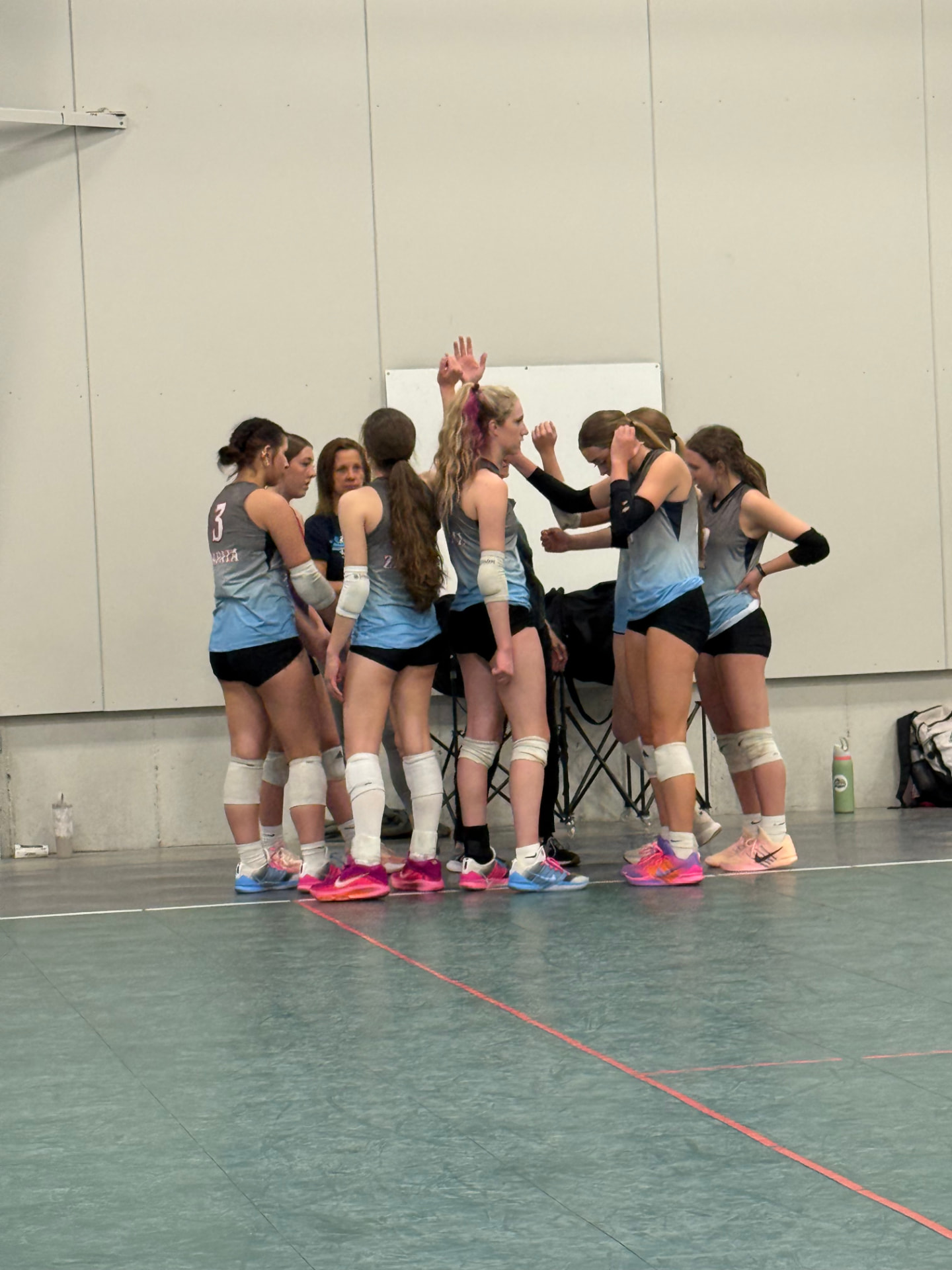 Zapata VBC team huddle in blue and grey jerseys